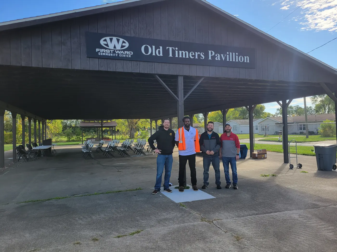 The H-Finity team standing beside the Old Timers Pavilion sign